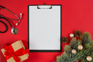 Celebrating Christmas in health care. Flat lay top view. Stethoscope, fir branches with ornaments on a white background. Top view, flat lay.