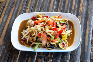 Green papaya salad in a plate on a table.