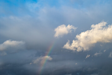 Fototapeta na wymiar Sky with clouds and a rainbow particle