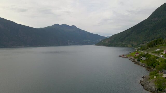 Aerial drone shot flying over Hardangerfjord and suspension bridge in Norway
