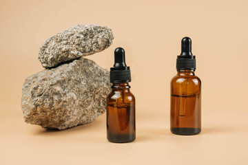 Mock-up of a set of empty cosmetic containers with pipettes made of amber glass on a beige...