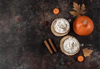 Pumpkin spice latte in a glass mug with cinnamon, nutmeg, and whipped cream.