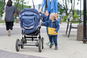 The baby rolls his stroller walking around the city