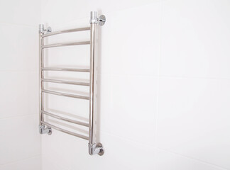 Modern stainless steel heated towel rail in the bathroom. Plumbing heating device, copy space for text