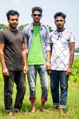 Three young men standing in the middle of green nature on a sunny day and their backgrounds blurred