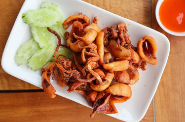 Deep fry sun-dried squid in white plate of wood table - Seafood at top view