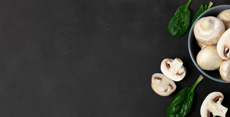 Raw mushrooms champignons on a black background.