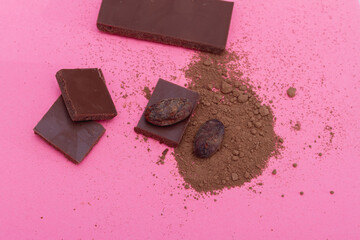 Chocolate, cocoa beans, cocoa powder on a pink background