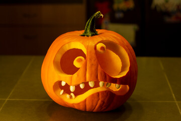 A jack-o-lantern isolated on the kitchen counter. Funny halloween pumpkin face.