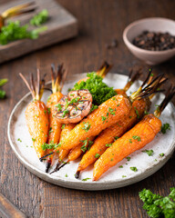 baked carrots on a plate on an old wooden table, close-up, selective focus