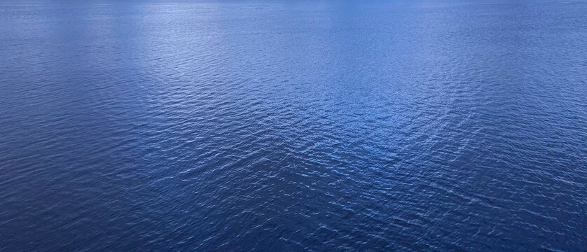 Blue shiny sea water background. Water calm glittering surface.