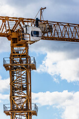 Tower crane close-up against the background of the cloudy sky. Shooting from a drone. Modern building technologies.