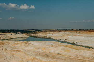 Sand quarry with exposed colored minerals, eqipment at the bottom the pit.