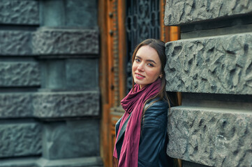 Naklejka premium A stylish young girl in a fashionable leather jacket on a city street .