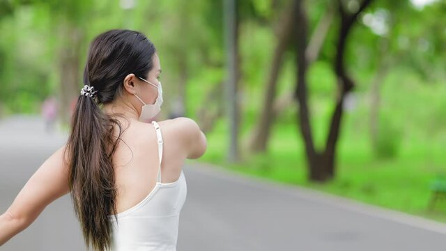 Asian runner jogging in the park during covid-19 pandemic. Working out in the days of the coronavirus.Fit woman jogging at outdoor .Healthy lifestyle concept. she have pois protective mask on face.
