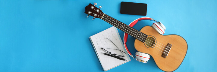 Guitar with headphones smartphones and notebook on blue background