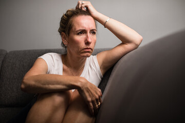 Depressed mid-aged woman at home feeling sad, lonely, anxious (color toned image)