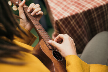 girl with dreadlocks closeup playing an acoustic instrument ukulele in autumn on the terrace - obrazy, fototapety, plakaty