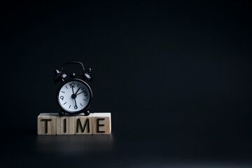 Clock and wooden blocks with TIME words on a black background. With copy space, design for vintage and business.