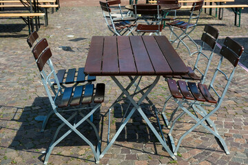 Leere Tische und Stühle im Außenbereich einer Gastronomie auf einem Platz - selektiver Fokus