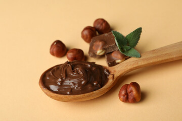 Spoon with chocolate paste, nuts, chocolate and mint on beige background