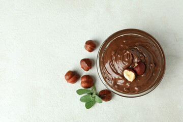 Bowl with chocolate paste, nuts and mint on white textured background