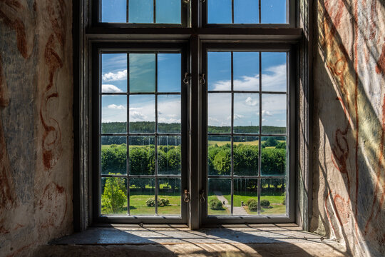 Beautiful summer landscape view with trees and sky seen through an ancient old castle window.