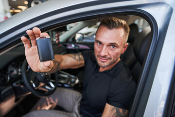 Obraz premium Confident driver demonstrating the keys from the new vehicle