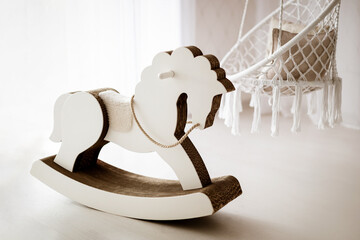 Light interior of children's room with wicker swings and white toy rocking horse