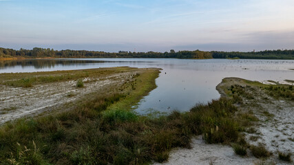 Aerial view of a picturesque place where transparent turquoise water of a forest lake meets a stony shore with trees in spring. captured with a drone. High quality photo