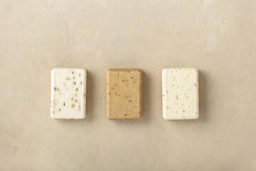 Three natural soap bars - lavender, cotton, patchouli - on natural stone background, flat lay