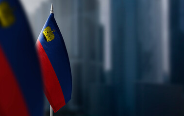 Small flags of Liechtenstein on a blurry background of the city - obrazy, fototapety, plakaty