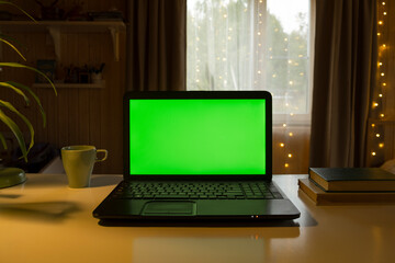 Laptop Computer with Green Mock-up Screen. Green Screen Device Stands on a Desk in the Living Room....