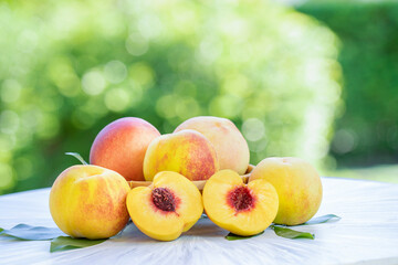 Yellow Peach with sliced on the wooden table over blurred greenery background, Fresh peach on wooden plate in wooden Background.