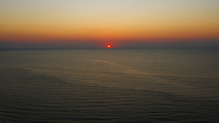 Panoramic view. Early sunrise over the Black Sea. Filmed by drone from bird's eye view. Full relax. Beautiful morning sunrise in light haze in autumn. Screensaver on computer, wallpaper for desktop.