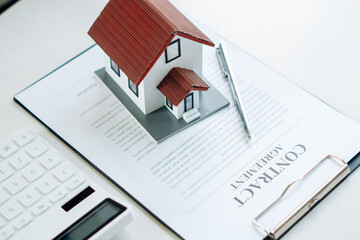 houses model and contract books, contact for home purchases, home insurance and real estate purchase concept.