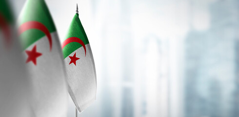 Small flags of Algeria on a blurry background of the city