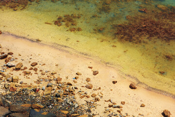 Close up of stones and clear water on the shore of a beach