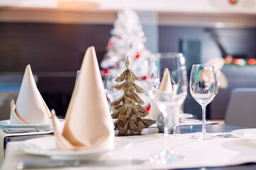 Table setting in the restaurant. Christmas tree on the background.