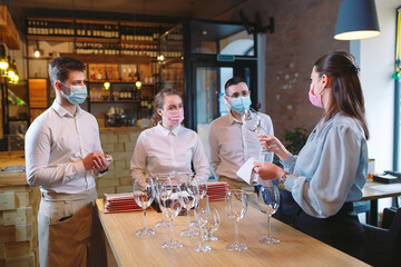 The waiters of the restaurant in a medical mask learns to distinguish between the glasses.
