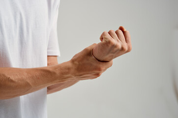 a man in a white t-shirt holding a hand pain in the wrist