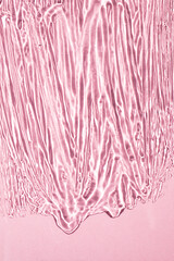 Transparent liquid gel texture on pink background. Close-up, top view. Vertical image.