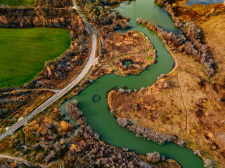 Aerial view of winding river and road in golden colored fall forest