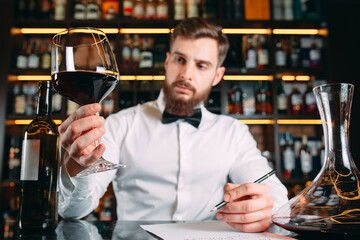 Young handsome man sommelier tasting red wine in cellar.