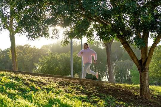 Fat man sprinting in the park with sunset light