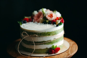 Cake is decorated with flowers on a dark background.