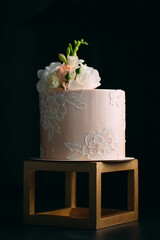 Cake is decorated with flowers on a dark background.