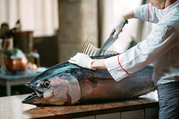 The chef cut up a big Tuna fish in the restaurant.