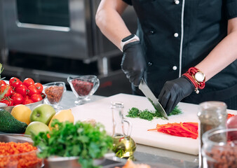 A Woman Chef cuts vegetables in the kitchen in a restaurant.