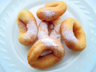 Donuts with powdered sugar.  Fried doughnuts made of yeast dough.